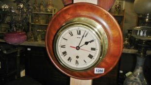 A brass ships clock on wood back