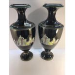 A pair of black glazed vases depicting classical scenes.