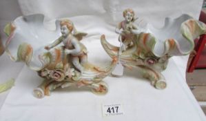 A pair of continental bisque porcelain conch shells surmounted with cherubs.
