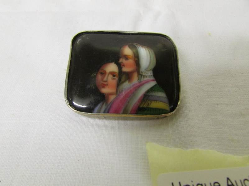 A hand painted porcelain brooch with 2 ladies.