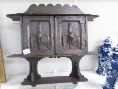 A carved oak wall cabinet, the doors carved with birds.