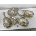 3 silver backed hair brushes, a silver backed hand mirror and a silver lidded pot.
