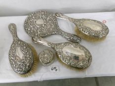 3 silver backed hair brushes, a silver backed hand mirror and a silver lidded pot.