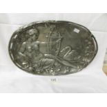 An oval white metal plaque depicting harpist with swan.