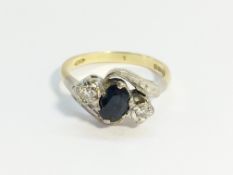 An 18ct cross over 2 diamonds and sapphire ring, size J half.