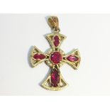 A 9ct gold cross in a gothic style set with red (possibly garnets) and white stones.