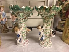 A pair of 19th century porcelain comports surmounted by cherubs. Approximate height 31.75cm.