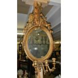 An oval gilded mirror with candle holder