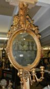 An oval gilded mirror with candle holder