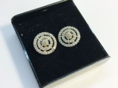 A pair of circle within a circle diamond and gold earrings.