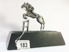 A hall marked silver horse and jockey jumping a fence on a heavy black marble base. H.