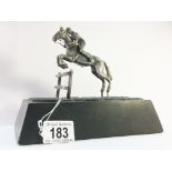 A hall marked silver horse and jockey jumping a fence on a heavy black marble base. H.