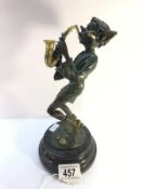 A bronze figure of a pixie playing a saxophone.