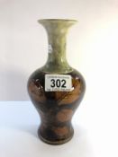 A small Royal Doulton vase depicting twigs with leaves in brown with a mottled grey/green top.