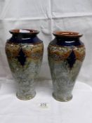 A pair of Royal Doulton vases showing swags of raised floral patterns in blue and brown on smooth