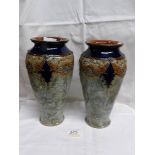 A pair of Royal Doulton vases showing swags of raised floral patterns in blue and brown on smooth
