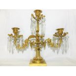 A gilded brass eagle surmounted candelabra with glass droppers