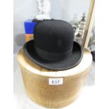 A bowler hat with wooden hat box.