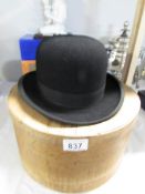 A bowler hat with wooden hat box.
