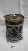 A Doulton Lambeth biscuit barrel with metal stand on three round feet and metal lid with a round