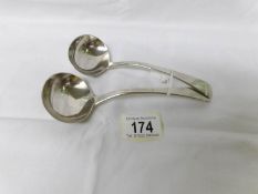 A pair of silver sauce ladles.