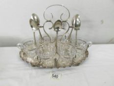 A silver plate tea stand with 6 glass teacups (missing one spoon).