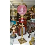 A brass and cranberry glass oil lamp.