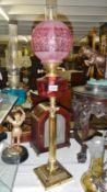 A brass and cranberry glass oil lamp.