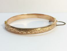 A rose gold bangle with chased gold work to top, hall marked J.G.C, Birmingham 1913.