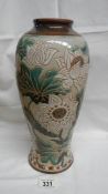 A large Doulton vase with large floral pattern in whites and greens on fawn ground.