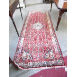 A red patterned carpet runner, 110 x 41.5 inches.