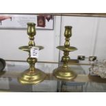 A pair of heavy brass candlesticks with drip trays.