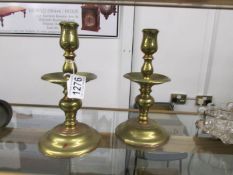 A pair of heavy brass candlesticks with drip trays.