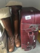 A pair of ladies knee high boots and a suitcase