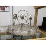A silver plated stand with 6 glass teacups and teaspoons (one spoon missing).