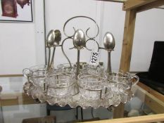 A silver plated stand with 6 glass teacups and teaspoons (one spoon missing).