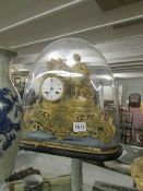 A gilded French clock under glass dome.