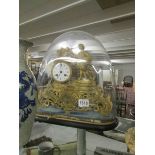 A gilded French clock under glass dome.