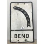 A vintage reflective illuminating 'BEND' road sign