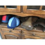 A leather saddle & 2 riding hats with silks