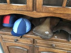 A leather saddle & 2 riding hats with silks