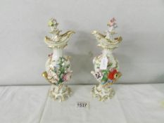 A pair of 19th century flower encrusted ewers with stoppers, 24 cm tall.