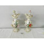 A pair of 19th century flower encrusted ewers with stoppers, 24 cm tall.