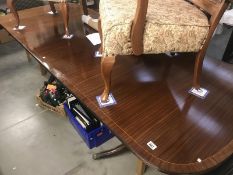 A dark wood stained extending dining table with string inlay and brass lion paw feet