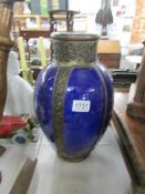 A large blue pottery vase with metal banding.