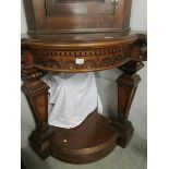A mahogany corner shelf with carved lion head supports,.