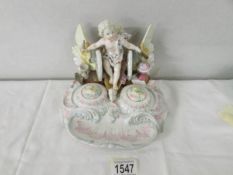 A 19th century porcelain ink stand depicting cherub on a winged chariot, 16 cm tall x 19 cm wide.