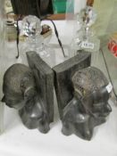 A pair of carved wood African head book ends and 2 cut glass decanters.