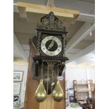 A wall clock with brass weights.