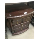 A dark wood stained small chest of drawers